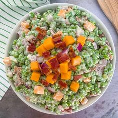 a bowl filled with peas and bacon on top of a table