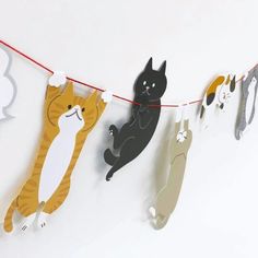 several cats hanging from a line on a string