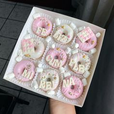 a box filled with pink and white decorated donuts in the shape of baby's first year