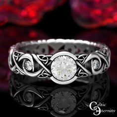 a white gold ring with an intricate design and a round diamond in the center, on a black background