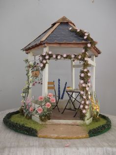 a miniature gazebo with chairs and flowers around it