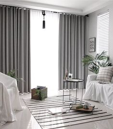 a living room with white furniture and curtains on the windowsills, along with a black and white striped rug