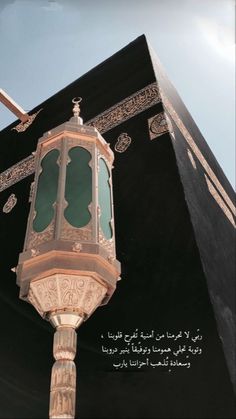 a tall black building with arabic writing on it's sides and a green light at the top