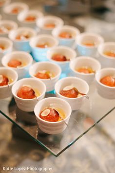 small bowls filled with food sitting on top of a glass table next to each other