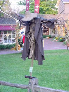 a scarecrow's hat is hanging on a post in the middle of a yard