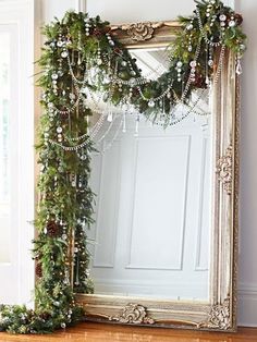 a large mirror sitting on top of a wooden floor next to a christmas wreath and garland