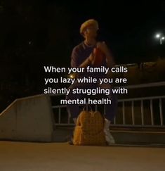 a man sitting on top of a yellow suitcase in front of a street sign that says, when your family calls you lazy while you are silently struggling with mental health