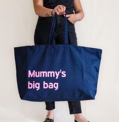 a woman holding a large blue bag with the words mummy's big bag on it