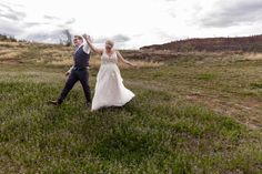 a bride and groom are dancing in the middle of an open field on their wedding day