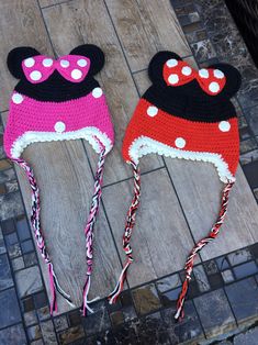 two crocheted mickey and minnie mouse hats on top of a wooden table next to each other