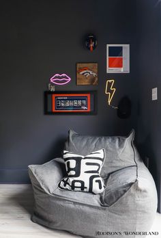 a gray bean bag chair in the corner of a room with pictures on the wall