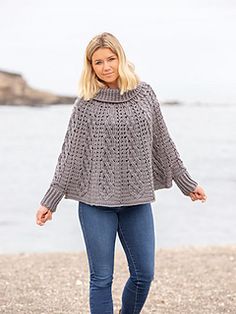 a woman standing on top of a beach next to the ocean with her hands in her pockets