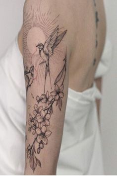 a woman with a tattoo on her arm has flowers and a bird in the sky