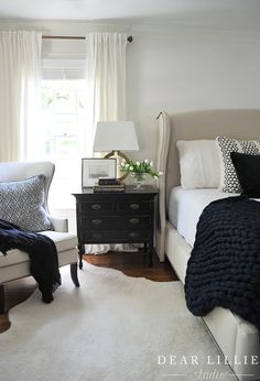 a bed room with a neatly made bed next to a window and a night stand