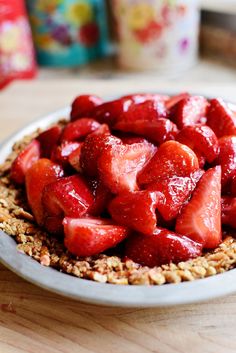 a bowl filled with sliced strawberries on top of a wooden table