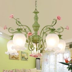 a green chandelier hanging from the ceiling in a living room filled with furniture