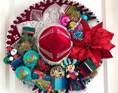 a red hat is on top of a wreath with other holiday decorations and ornaments around it