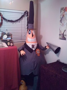 a man dressed as a scarecrow in an office with decorations on the desk and behind him