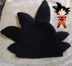 a black knitted dragon ball glove laying on top of a white towel next to a cartoon character