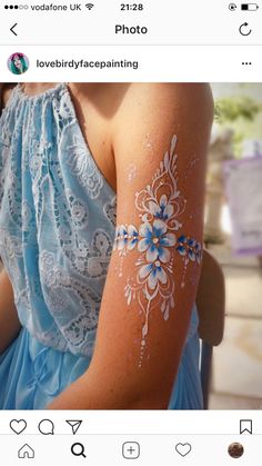 a woman's arm with white paint on it and blue flowers painted on the arm