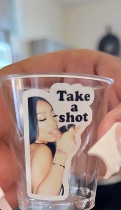 a person is holding a cup with a sticker on it and the words take a shot