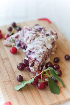 a wooden cutting board topped with grapes and cheese covered in icing on top of it