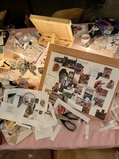 a table covered with pictures and other items on top of a pink clothed tablecloth