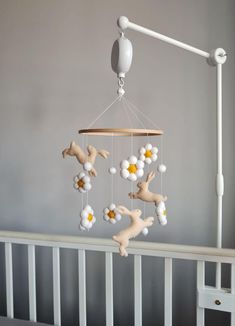 a baby crib with a mobile hanging from it's side and flowers in the middle