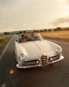 two people driving in an old fashioned convertible car