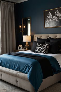 a bed with blue sheets and pillows in a bedroom next to a window, framed artwork on the wall