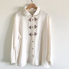 "vintage cream long sleeve blouse excellent condition Size 14W 100% polyester embroidered detail  jeweled buttons, padded shoulders  Approx. measurements: Length: 28\" Arms:  24\" Pit to pit: 26\"" Classic Long Sleeve Tops With Embellished Collar, Classic Long Sleeve Top With Embellished Collar, White Long Sleeve Tops With Embellished Collar, Classic Embroidered Cream Top, Classic Cream Embroidered Top, White Embellished Long Sleeve Blouse, Embroidered Long Sleeve Cream Blouse, Embroidered Cream Button-up Top, Vintage Embroidered Beige Blouse