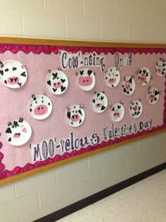 a bulletin board is decorated with paper plates and cow faces on the wall in a school hallway