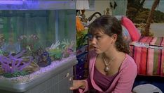 a woman looking at an aquarium in a room with other items on the floor and walls