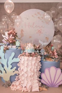 a table topped with cakes and desserts under bubblegum balloons at a mermaid themed birthday party