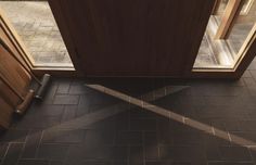 the door is open to let in some light and shadows on the tile flooring