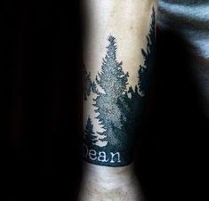 a man's arm with a forest tattoo on it and the words mean written in black ink