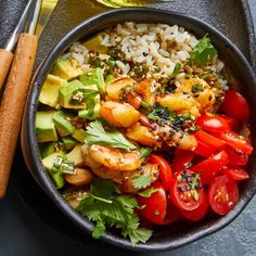 a bowl filled with shrimp, rice and vegetables next to a spoon on a table