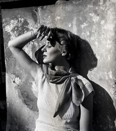 black and white photograph of a woman with her hands on her head, leaning against a wall