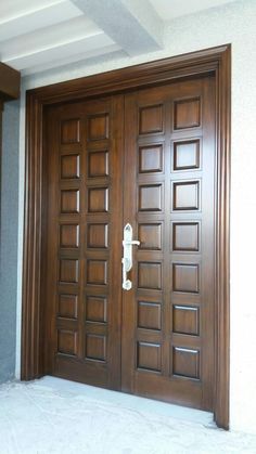 two wooden doors with white handles in front of a building