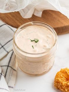 a jar filled with white sauce next to some fried food