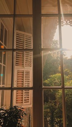 the sun shines through an open window in front of a house with shutters