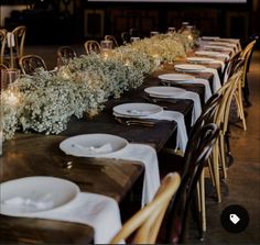 a long table is set with white plates and place settings