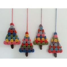 three crocheted christmas trees hanging from strings on a white wall with red, yellow, blue and green yarn