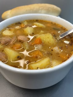 a white bowl filled with soup next to a loaf of bread