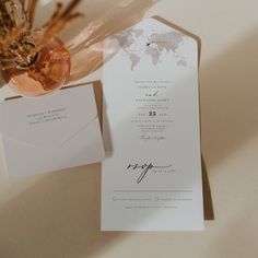 the wedding stationery is laid out on top of an envelope and some dried flowers