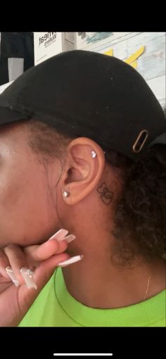 a woman with ear piercings on her left side is looking at the camera while she's wearing a baseball cap