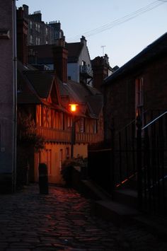 a cobblestone street at night with buildings in the background and a light on