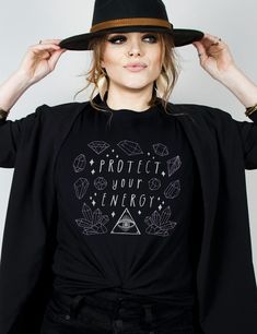 Unleash your inner power with the Protect Your Energy Shirt. Designed for witchy souls and modern mystics, this shirt is crafted from 100% breathable cotton, flawlessly merging witchcraft aesthetics with contemporary comfort. Elevate your everyday style and embrace your spiritual journey with this unique addition to your wardrobe staples.Choose from a variety of plus sizes up to 3XL for a roomy fit, or size up for an oversized look.Surprise any of your witchy friends with a gift they would love! Plus Size Witchy Outfits Fall, Casual Witchy Outfit, Witchy Shirt Ideas, Spiritual Tshirt Ideas, Witchy Hippie Aesthetic, Witchy T Shirt Ideas, Witch Outfit Modern, Witch Tshirt Ideas, Cowgirl Witch