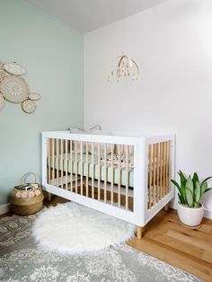 a white crib in a baby's room next to a potted plant