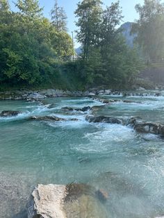 the water is blue and green with rocks in it, as well as some trees